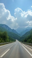 A scenic road winding through lush green mountain valleys under clouds