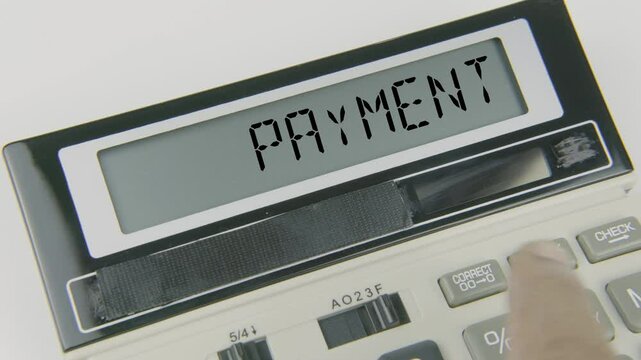 Payment text or words displayed on a calculator's LED screen as a hand types numbers, symbolizing financial transactions, processing, and managing payments in various financial and business contexts