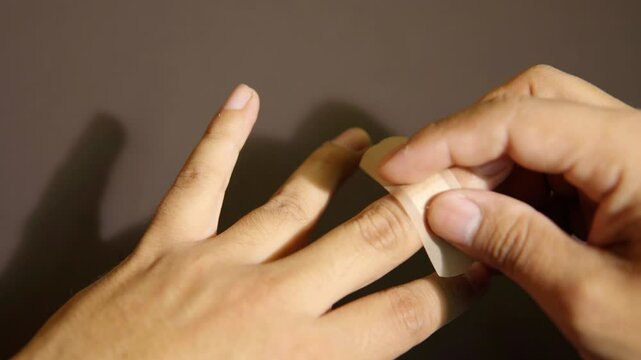 Placing a band-aid on a finger of a hand with an injury, first aid and care