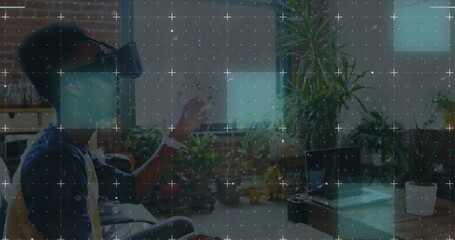 Light trails over grid network against african american man wearing vr headset at office