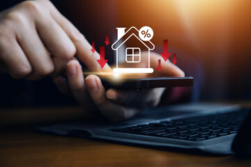 Businessman use smartphone with virtual home icon and down arrow for economical real estate and...