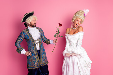 Fototapeta premium A Couple in Historic Costumes Enjoy a Masquerade Party Against a Pink Background