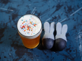 top view of Easter beer glass in sprinkles, two eggs with bunny ears