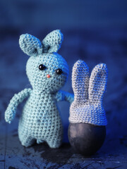 Knitted toy Easter bunny and egg with bunny ears hat on blue background