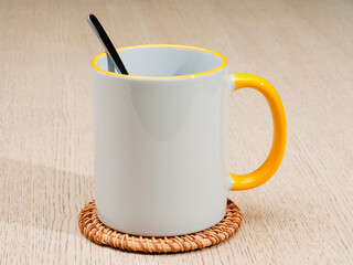 Two-tone 11oz mug on the mug coaster on the table. Mug with tea spoon. Mug with yellow handle and inner part.