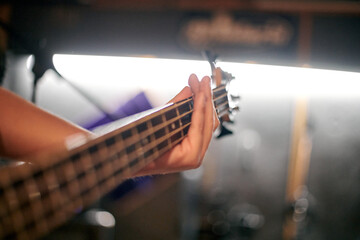 Focused view of musician hand playing bass guitar during performance, highlighting strings and...