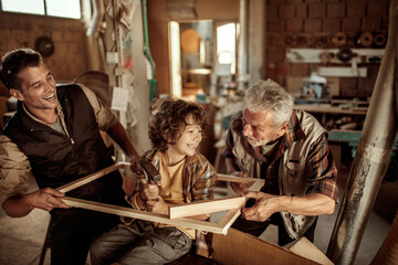 Three male generations working together on a woodworking project in family workshop