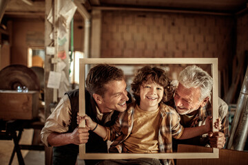 Three male generations working together on a woodworking project in family workshop