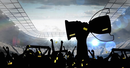 Golden confetti falling over silhouette of fans cheering and sports stadium in background