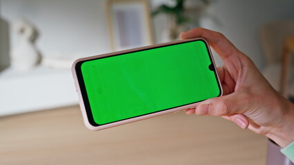 Hand holding horizontal mockup mobile phone in modern apartment closeup. 