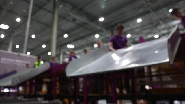 Blurred motion of packages moving quickly on a conveyor belt at a high-speed logistics facility. Efficient delivery workers sort packages in a logistics center