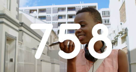 Image of numbers changing over woman talking on smartphone