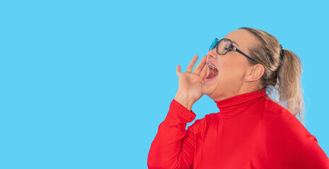 Woman in red turtleneck passionately communicating in front of a vibrant blue background during an...