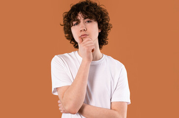 Thoughtful young person in casual attire posing against a vibrant background while contemplating...