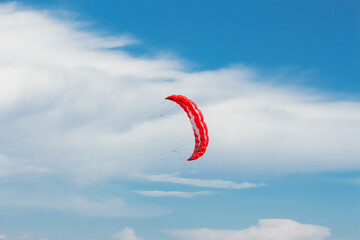 red parachute flying in blue sky with white clouds