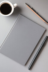 Blank notebook with cup of coffee and pen on gray background