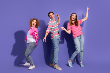 Fototapeta premium Group of young friends posing together with upbeat expressions and colorful outfits on a purple background