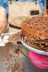 Pastry chef decorating chocolate cake with chocolate shavings in kitchen