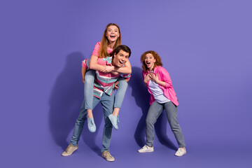 Fototapeta premium Young friends enjoying playful time together on a purple background, showcasing friendship and happiness