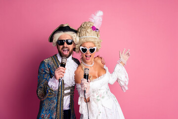 Elegant Couple in Vintage Costumes Singing Together in Front of a Pink Background