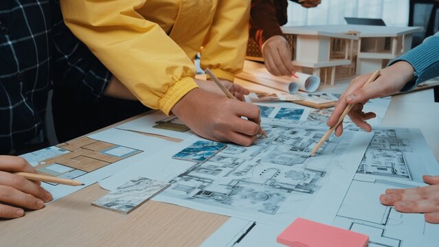 A vibrant collaborative design session showcasing diverse hands engaged in creating architectural blueprints and models, highlighting teamwork and creativity in a bright workspace. SACTR