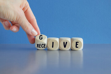 Dice form the words give and receive. Beautiful blue background, gray table. Businessman hand....