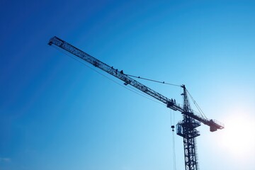 large construction crane silhouetted against clear blue sky