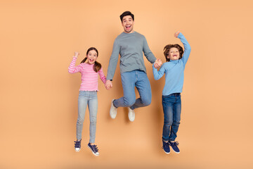 Fototapeta premium Happy family jumping joyfully against beige background showcasing positive energy, bonding and love in casual outfits with cheerful smiles