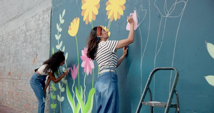 Women, students and painting mural on wall of creative decoration, community project and artistic freedom. People, artist and diy for public art, flower design and local culture for therapeutic hobby