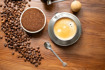 coffee beans, a cup of espresso and ground coffee on brown background