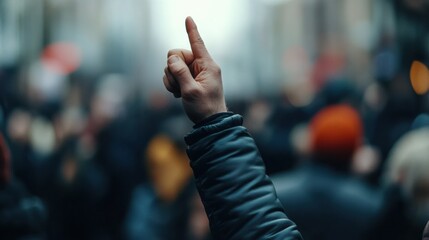 Raised hand gesturing with confidence amidst a blurred crowd during a significant public gathering