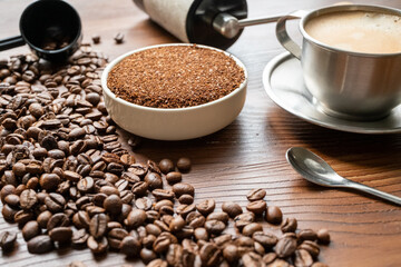 coffee beans, a cup of espresso and ground coffee on brown background