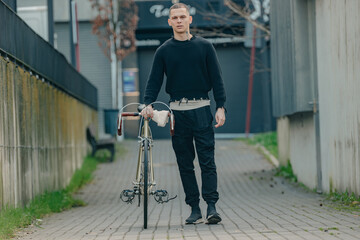 young man with bicycle walking on the street