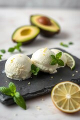 Avocado ice cream with citrus zest, mint garnish, and sliced fruit accents on a dark platter.