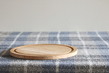 Round wooden chopping board resting on checkered tablecloth