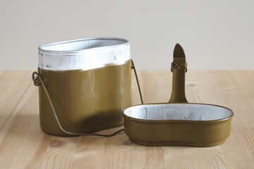 Military mess kit open on wooden table displaying pot and pan