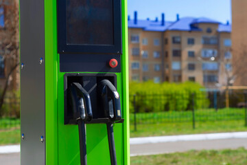 Electric vehicle charging station with green color in an urban residential area, surrounded by apartment buildings and greenery.