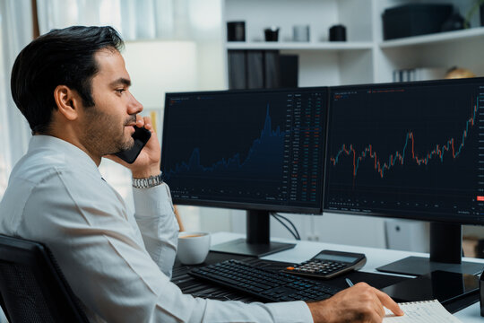 Trader businessman calling to consultant or partner with two stock exchange investment, compare data analysis to invest high profit value dynamic financial technology stock market at office. Surmise. - Powered by Adobe