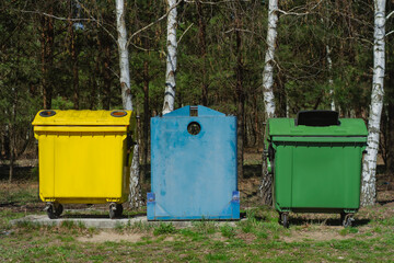 Three colorful recycling bins, yellow, blue, and green stand in forest. Eco-friendly waste sorting...