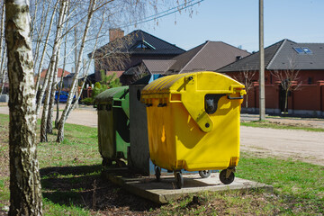 Three colorful recycling bins yellow, green, and blue stand in a residential area surrounded by...