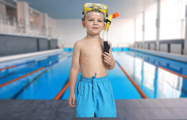Cute little boy in trunks with snorkeling equipment at indoor swimming pool