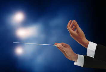 Conductor with baton in concert hall, closeup