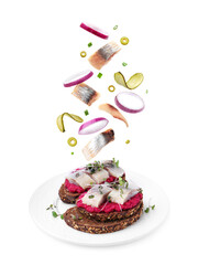 Tasty bruschettas with herring and flying ingredients on white background