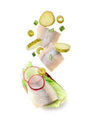 Tasty bruschetta with herring and flying ingredients on white background