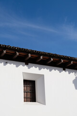Traditional Colonial Window with Shadows on White Wall Against Blue Sky