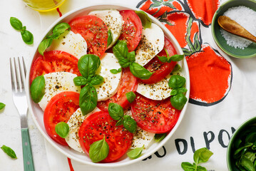 Traditional Italian caprese salad with tomatoes, mozzarella and basil on a white plate