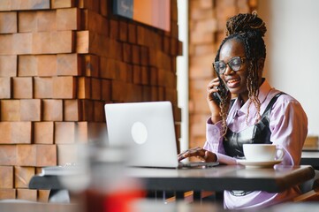 Portrait of an african american young woman sitting at cafe with laptop writing her blog