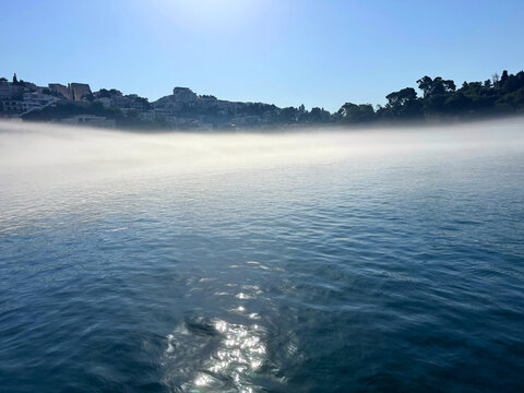 Mist over sea and town in summer morning.