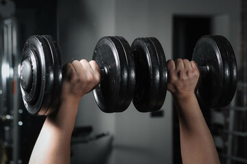 Muscular guy in the gym with dumbbells.