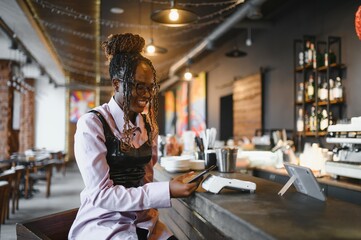 African woman paying by phone in a cafe.